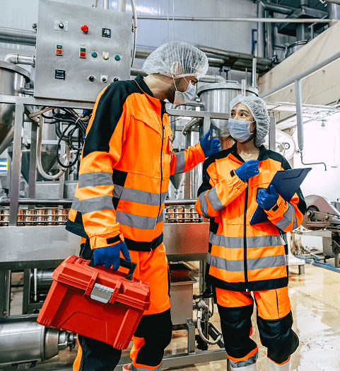 Two plant engineers in high-visibility gear carrying out maintenance on a production line